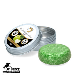 Metal tin with its lid open, revealing a green round shampoo bar; label says 'Hi Gloss Shampoo Bar' with apple imagery and the De Jaer logo bottom left.
